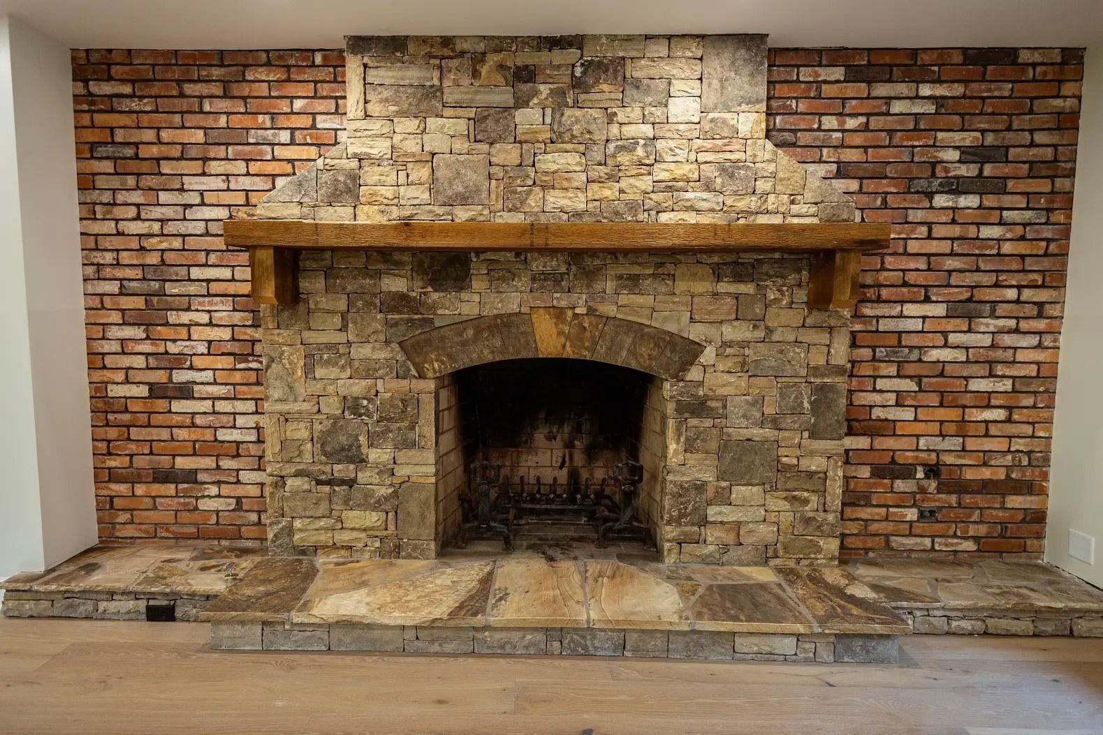 A large stone fireplace with a wooden mantle in a living room.