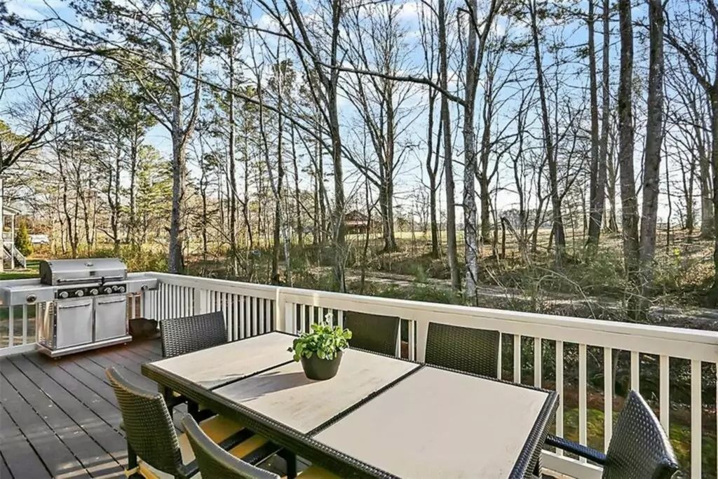 There is a table and chairs on the deck with a view of the woods.