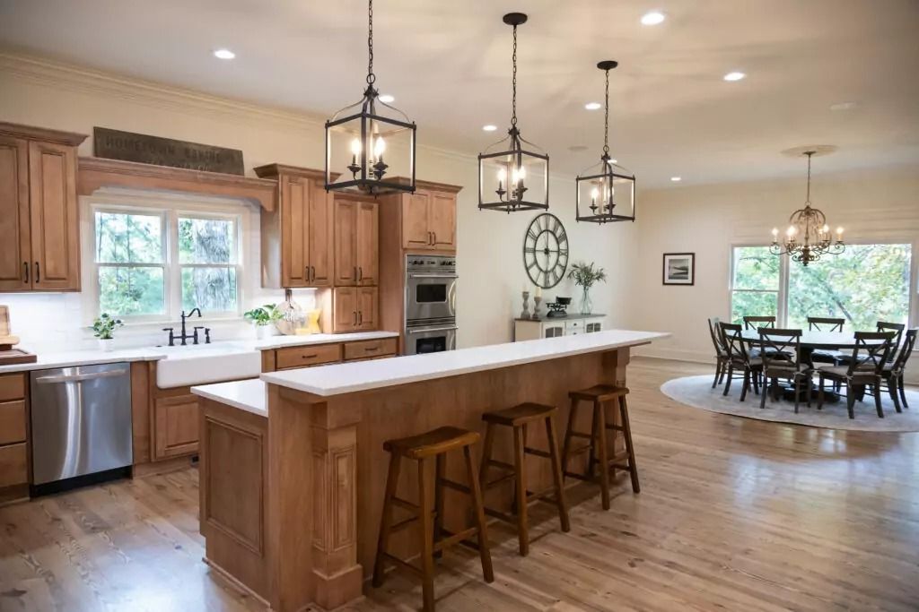 A kitchen with wooden cabinets , white counter tops , stainless steel appliances and a large island.