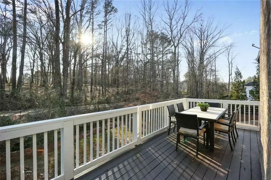 A deck with a table and chairs and trees in the background