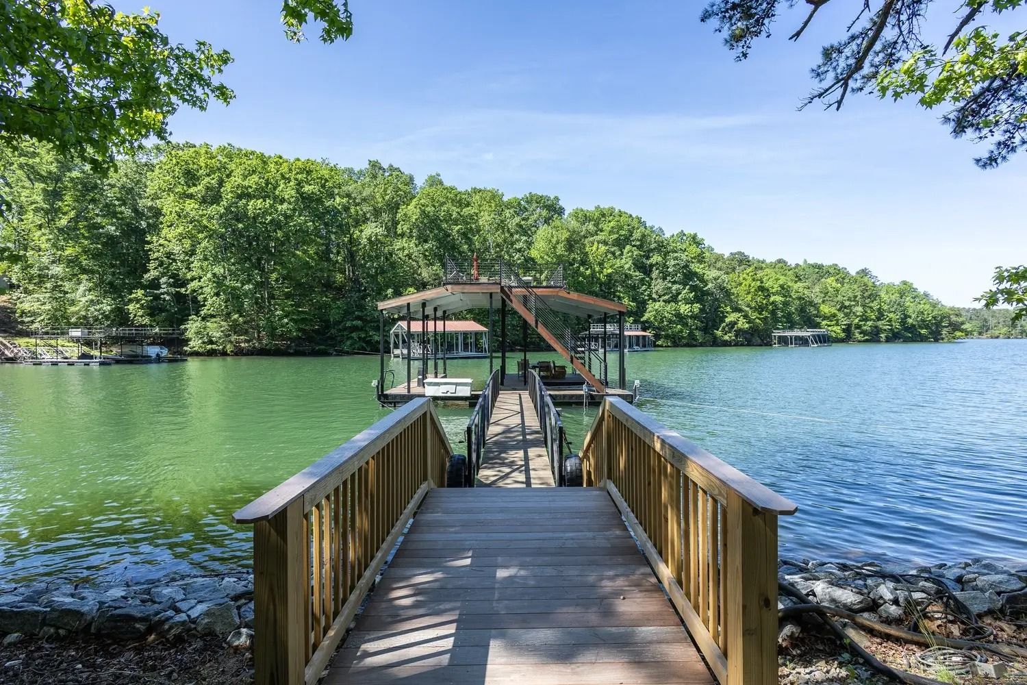 A wooden dock leading to a lake surrounded by trees.