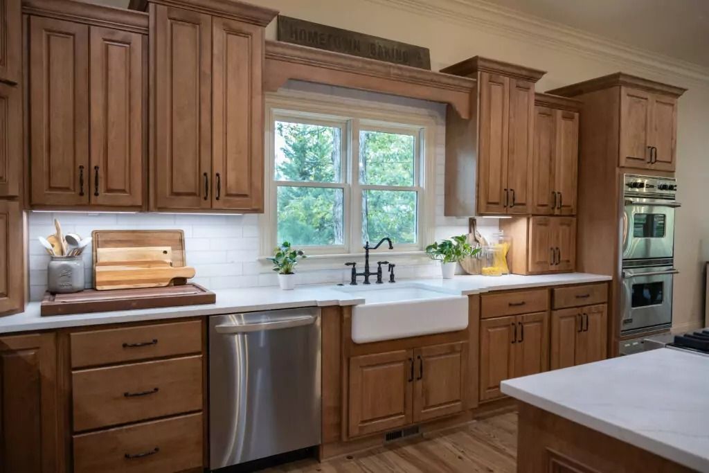 A kitchen with wooden cabinets , stainless steel appliances , a sink and a window.
