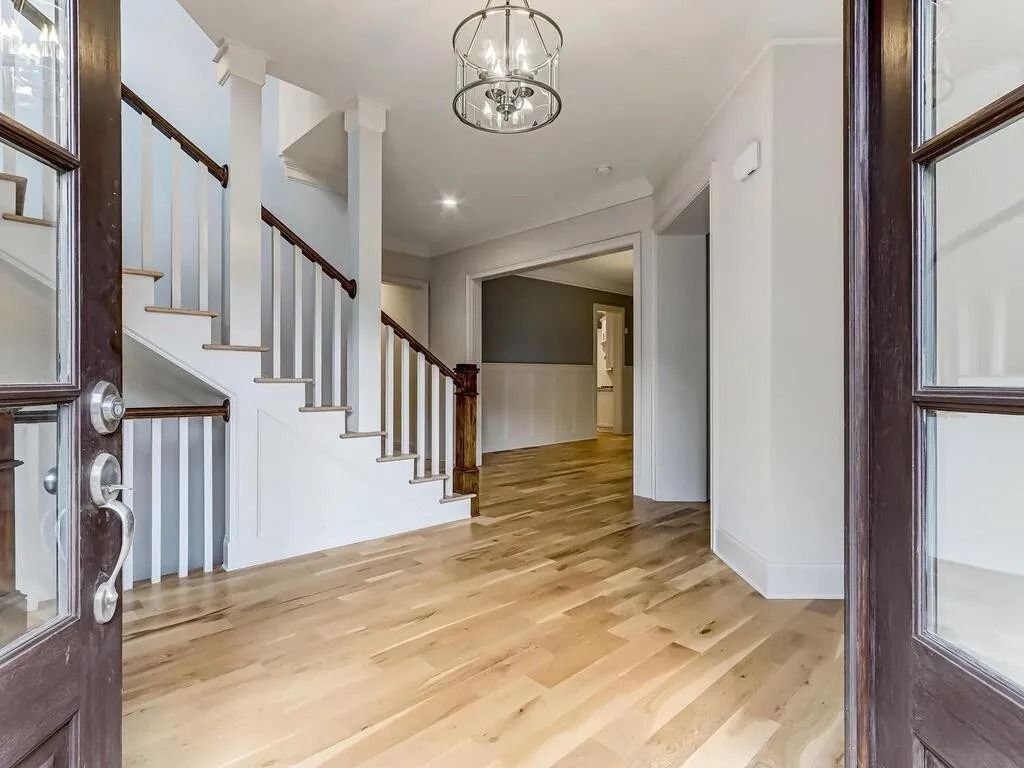 A hallway with hardwood floors and stairs in a house.