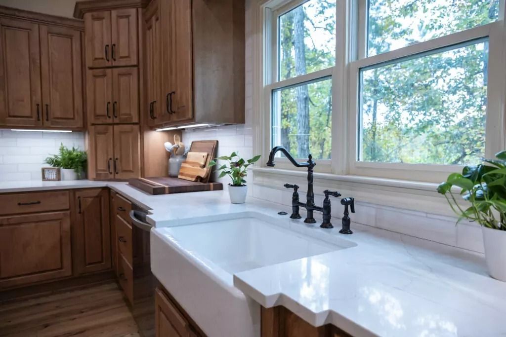 A kitchen with a sink and a window with trees in the background.