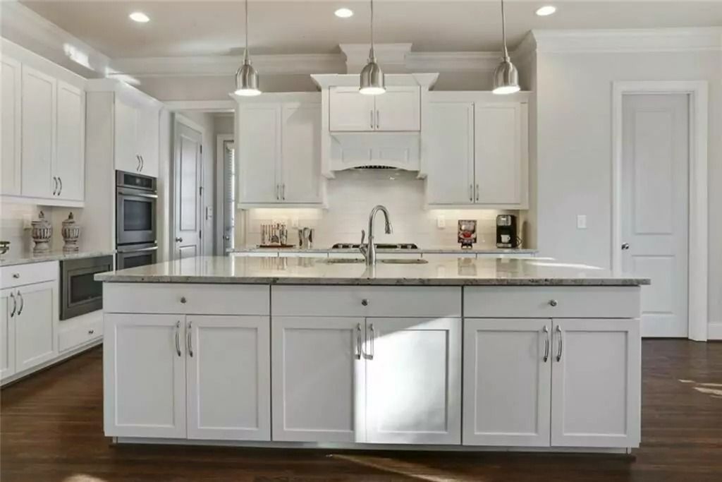 A kitchen with white cabinets and a large island in the middle.