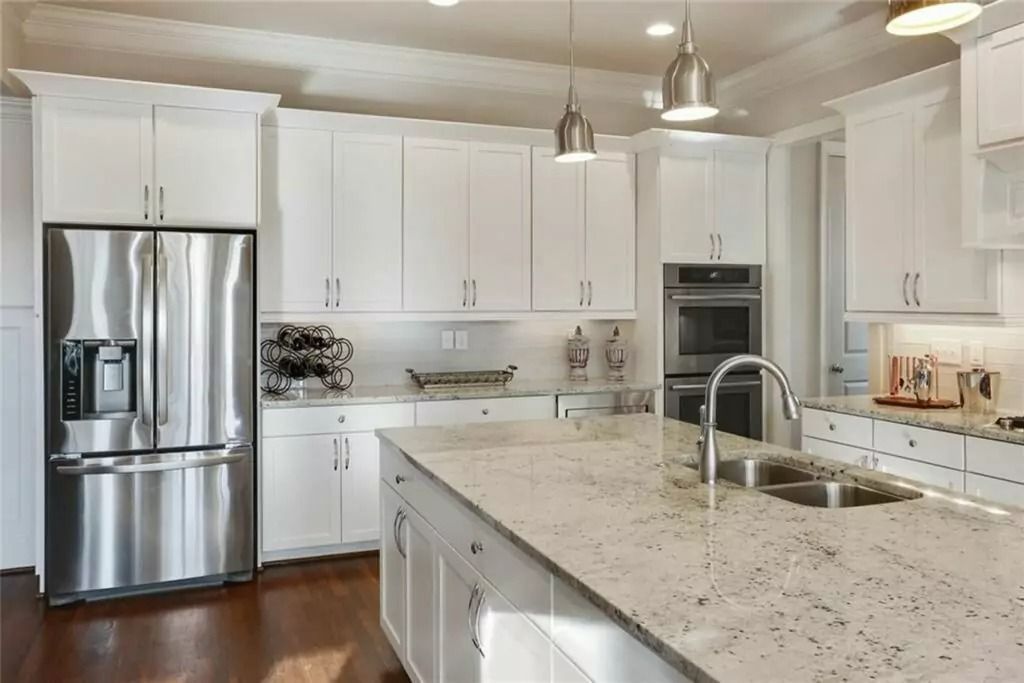 A kitchen with white cabinets , stainless steel appliances and granite counter tops.
