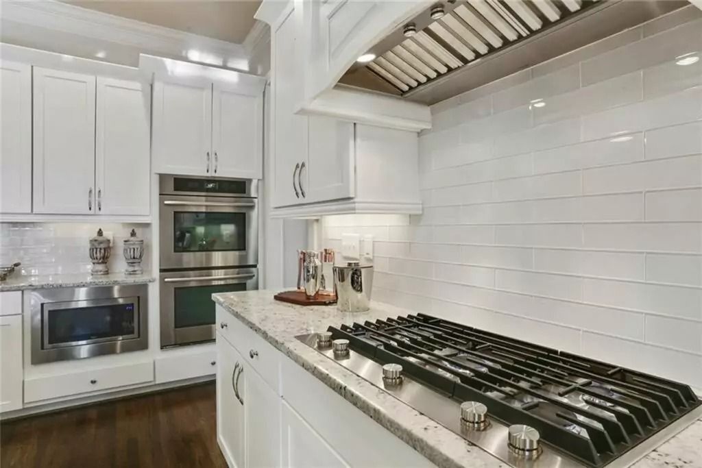 A kitchen with white cabinets and stainless steel appliances and a stove top oven.