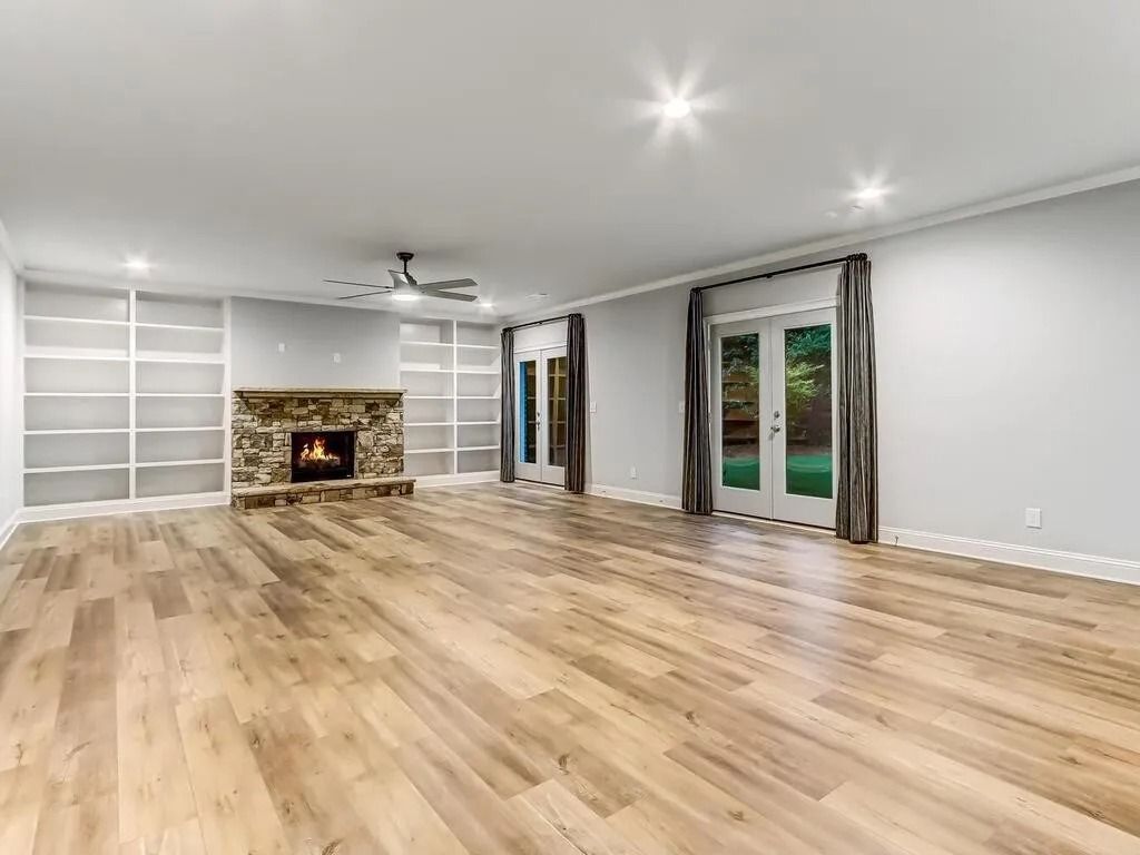 An empty living room with hardwood floors and a fireplace.