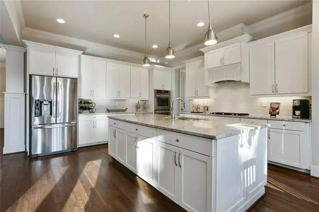 A large kitchen with white cabinets and stainless steel appliances