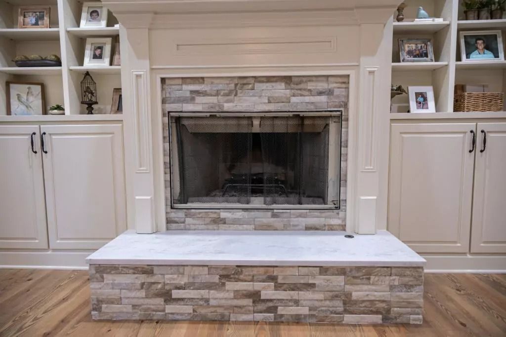 A living room with a fireplace and built in shelves.