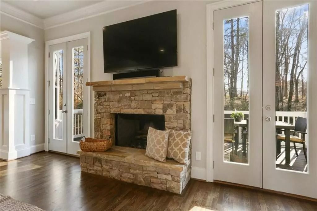 A living room with a stone fireplace and a flat screen tv.