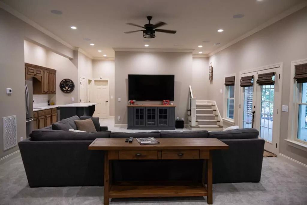 A living room with a couch , table , television and ceiling fan.