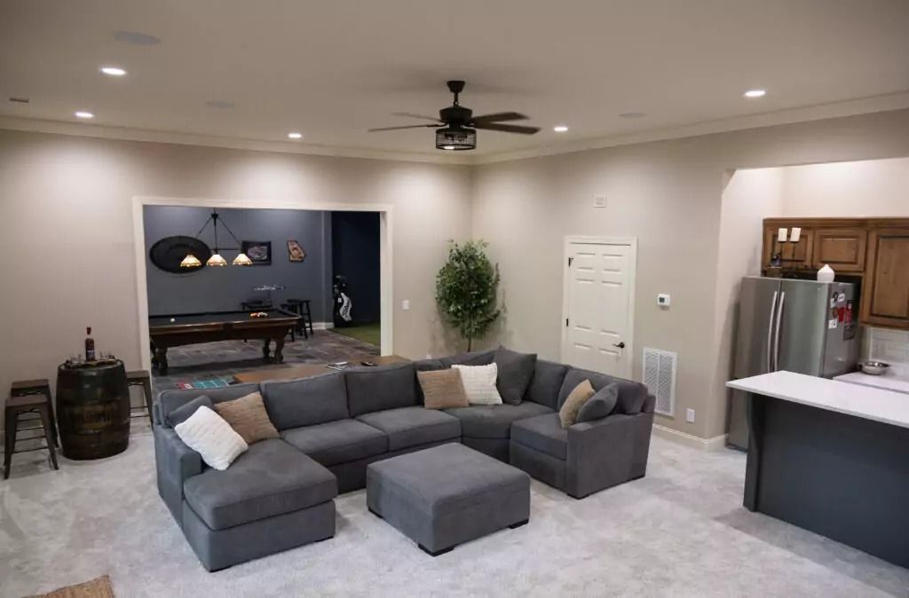 A living room with a large sectional couch and a ceiling fan.