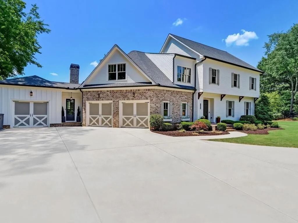 A large white house with two garage doors and a large driveway.