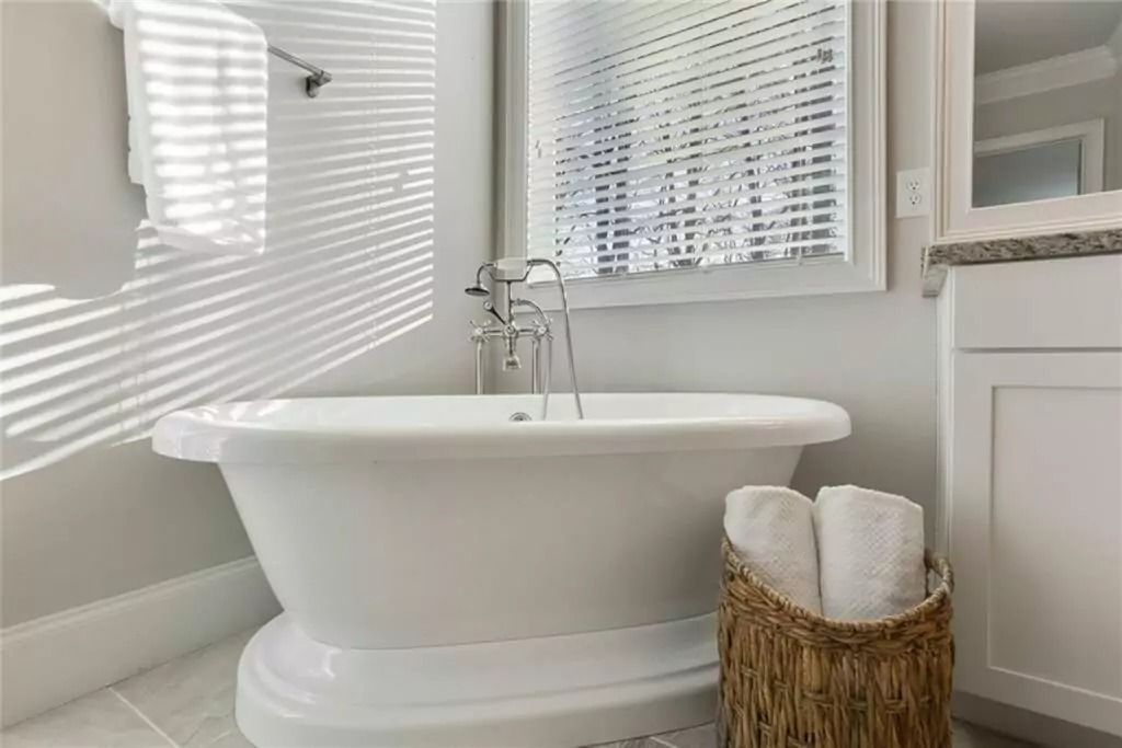 A bathroom with a tub and a basket of towels.