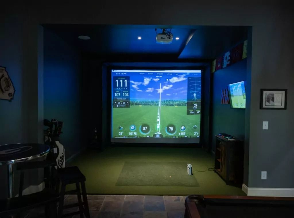 A room with a pool table and a large screen on the wall.