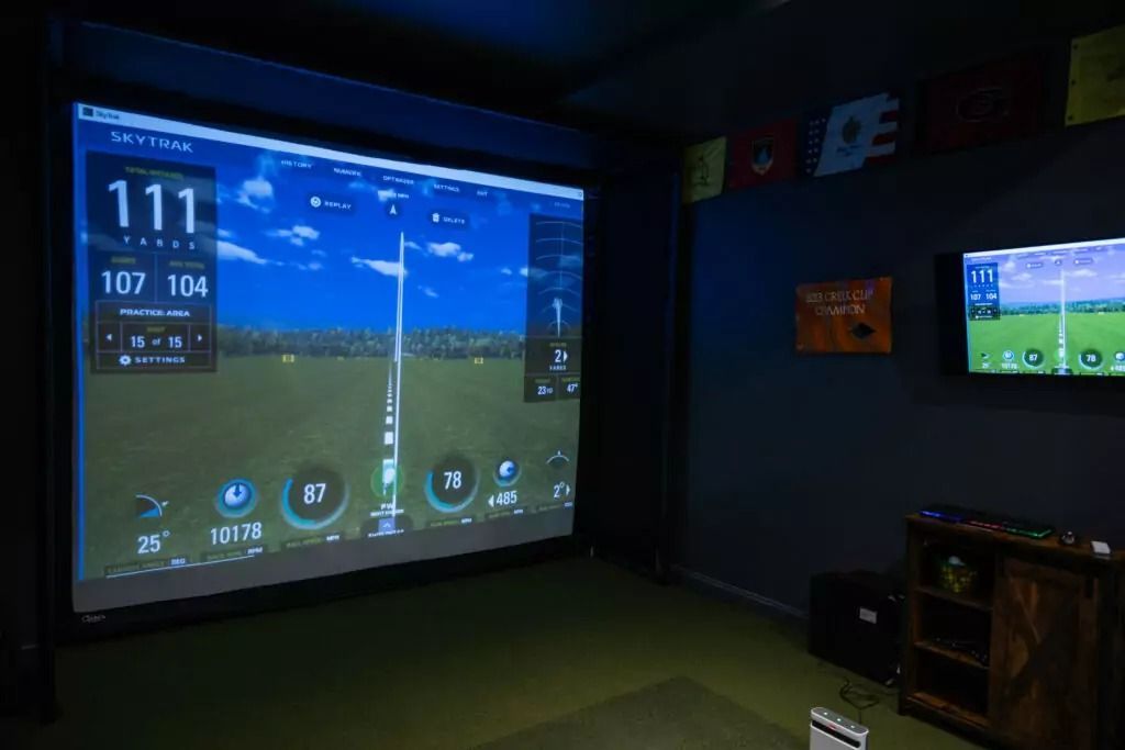 A room with a projector screen and two televisions.