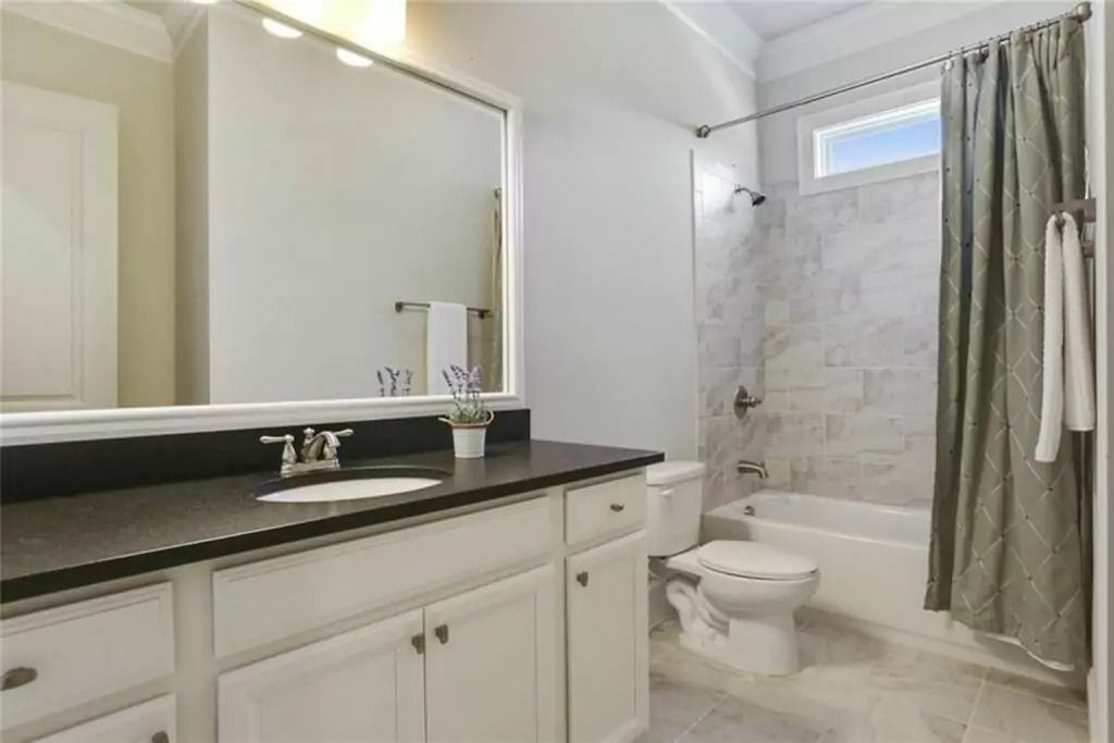 A bathroom with a sink , toilet , shower and mirror.