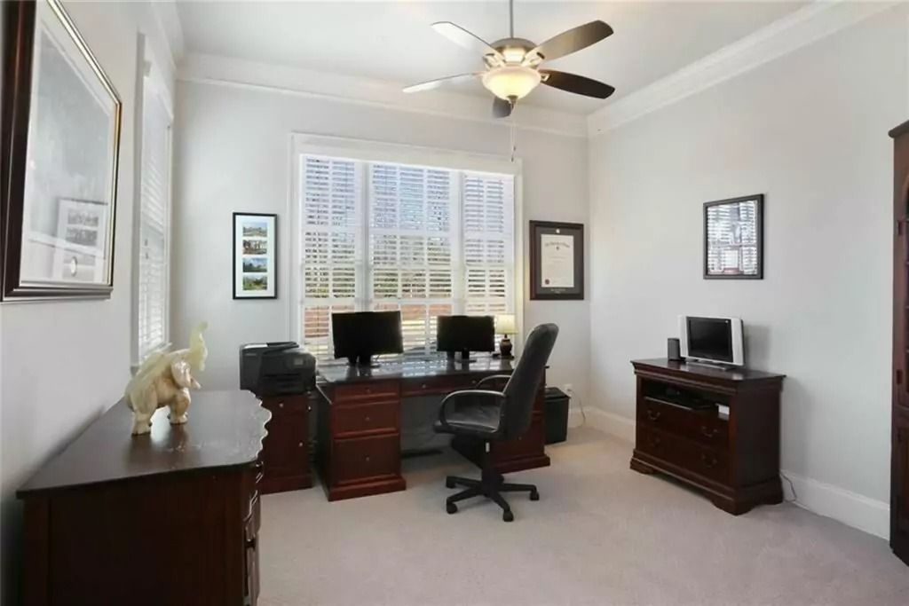 A home office with a desk , chair , computer and a ceiling fan