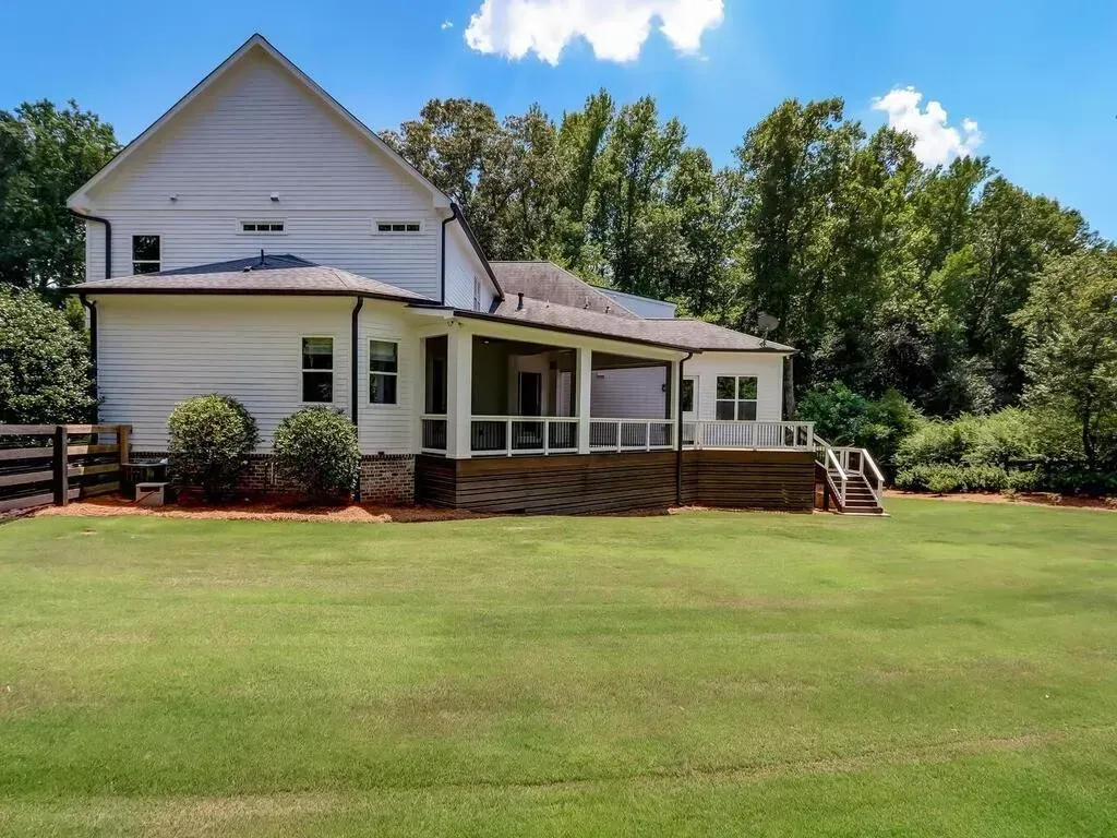 A white house with a large porch and a fence in front of it
