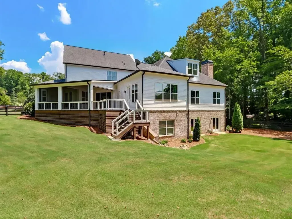 The back of a large house with a large lawn in front of it.