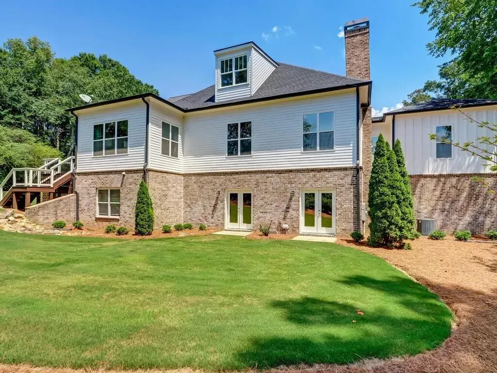 The back of a large white house with a large lawn in front of it.