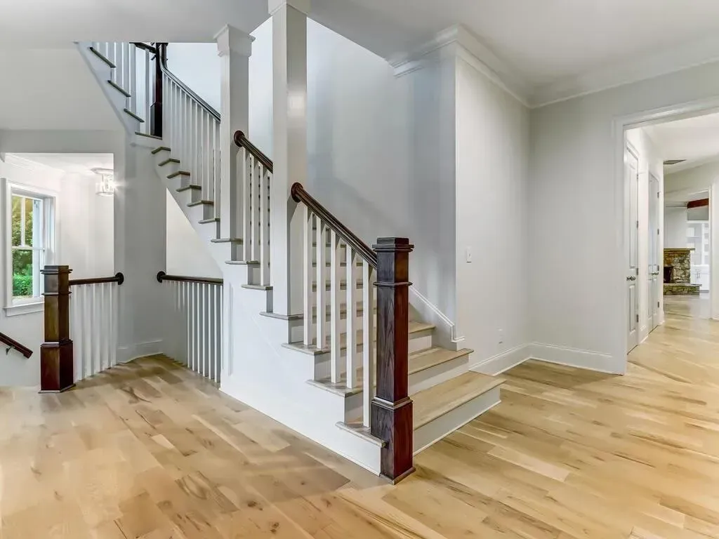 There is a staircase in the middle of the room with hardwood floors.