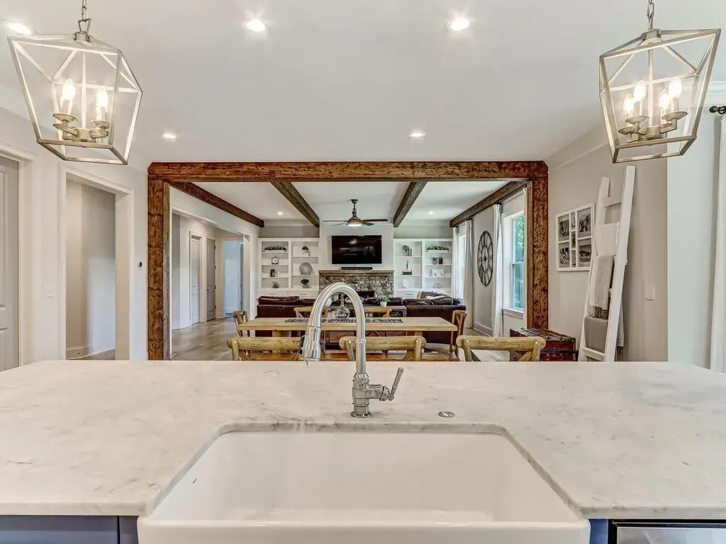 A kitchen with a sink and a dining room in the background.