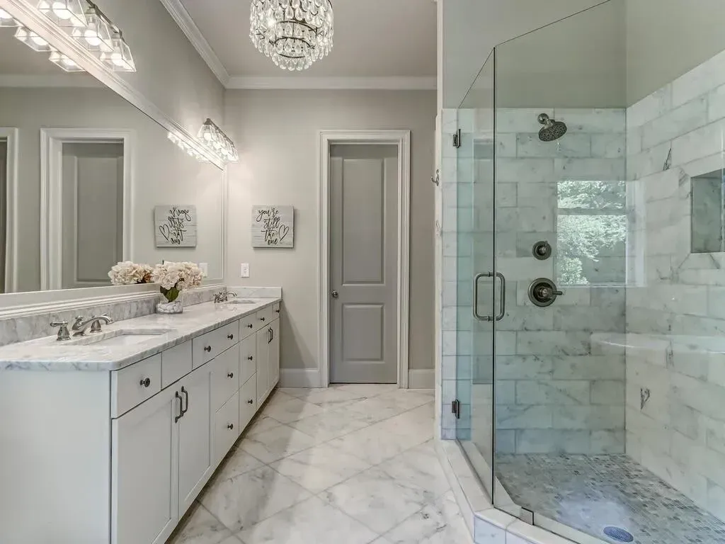 A bathroom with two sinks and a walk in shower.