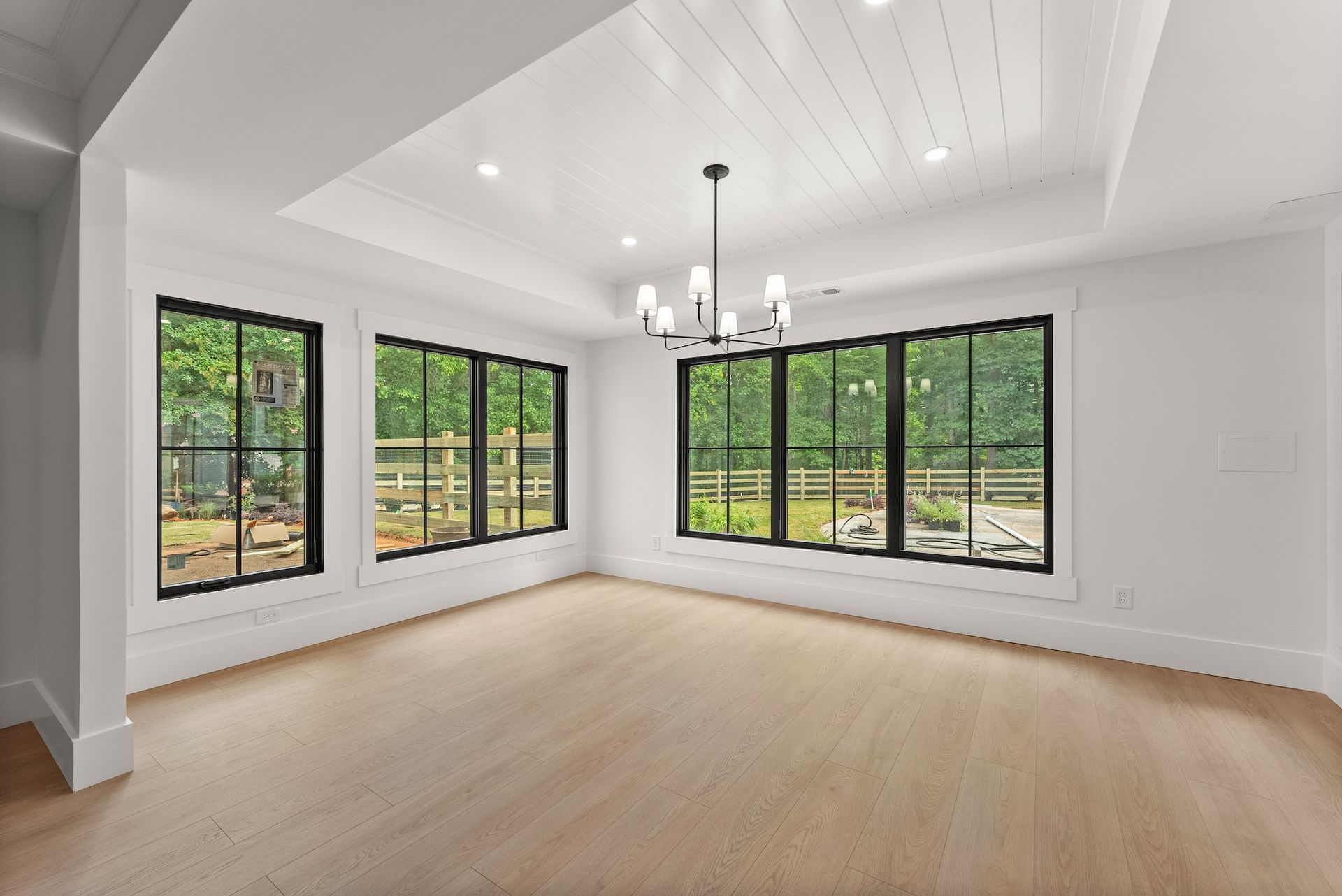 An empty living room with lots of windows and a chandelier