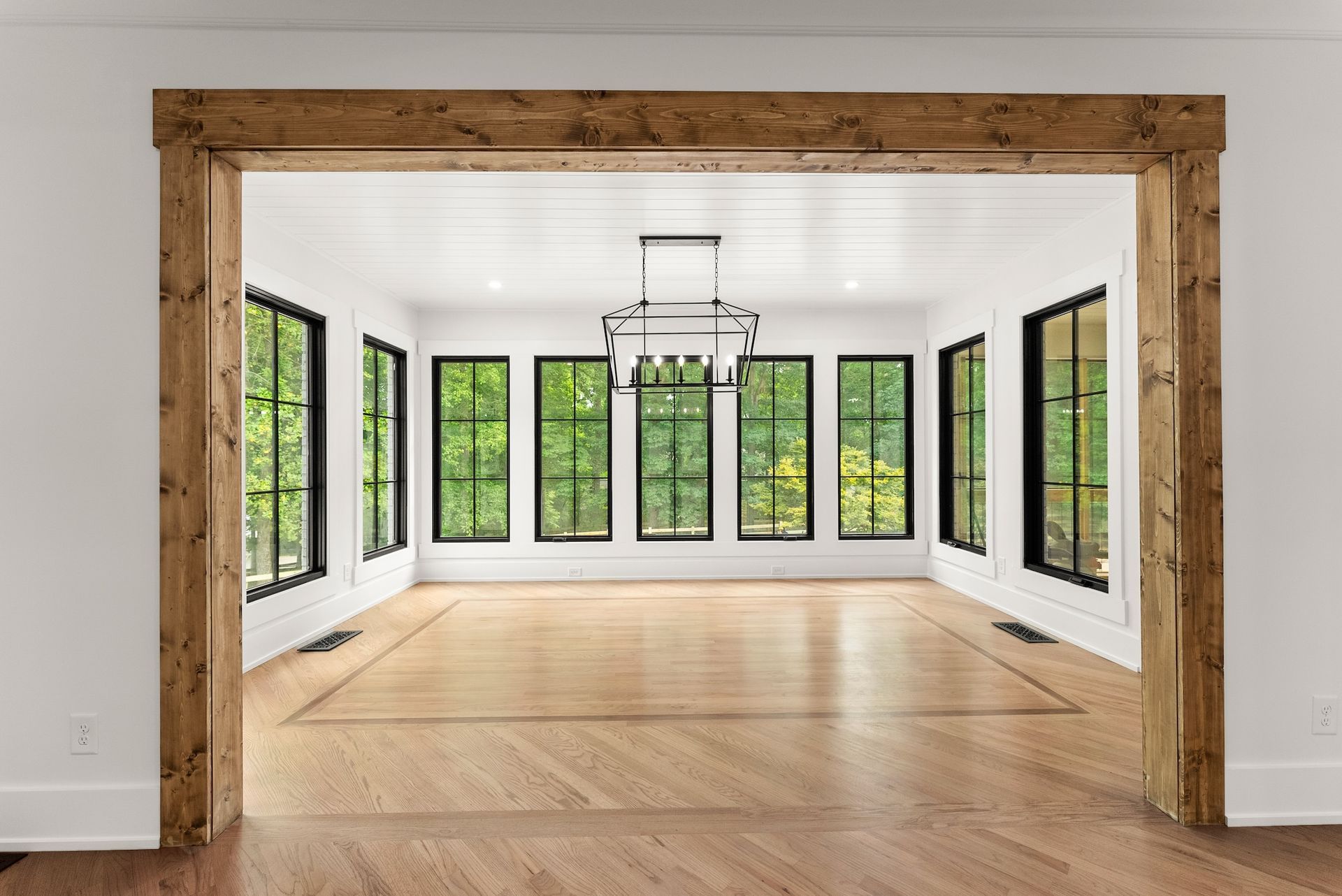 A large empty room with lots of windows and wooden beams.
