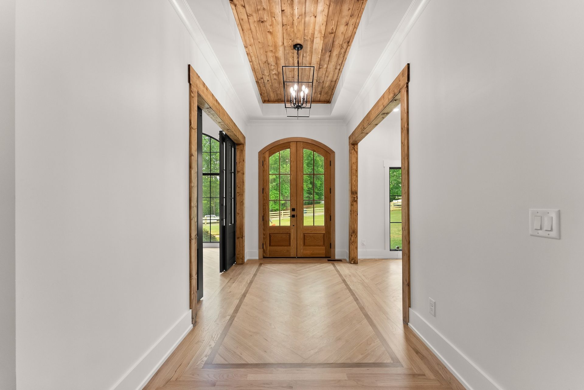 A hallway with a wooden door and a chandelier hanging from the ceiling.