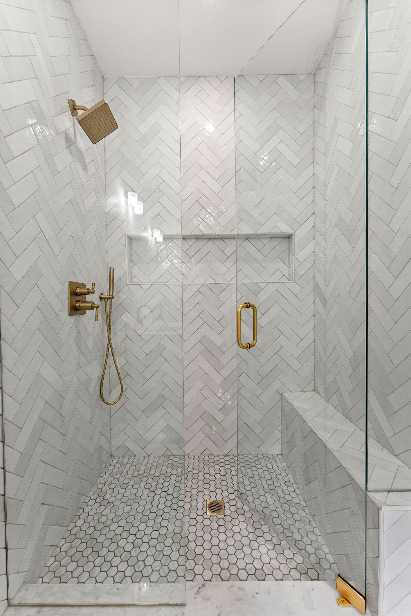 A walk in shower with a glass door and a bench.
