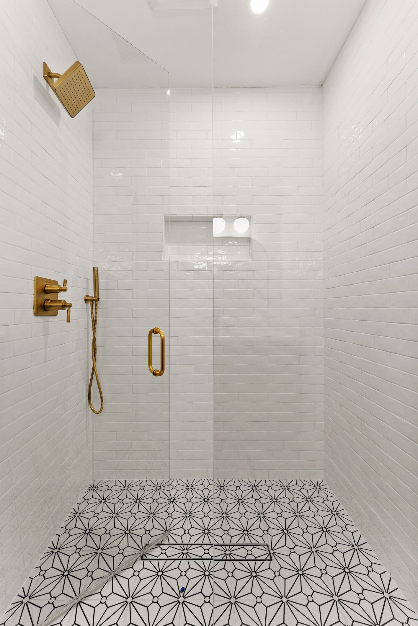 A bathroom with a walk in shower and a black and white tile floor.