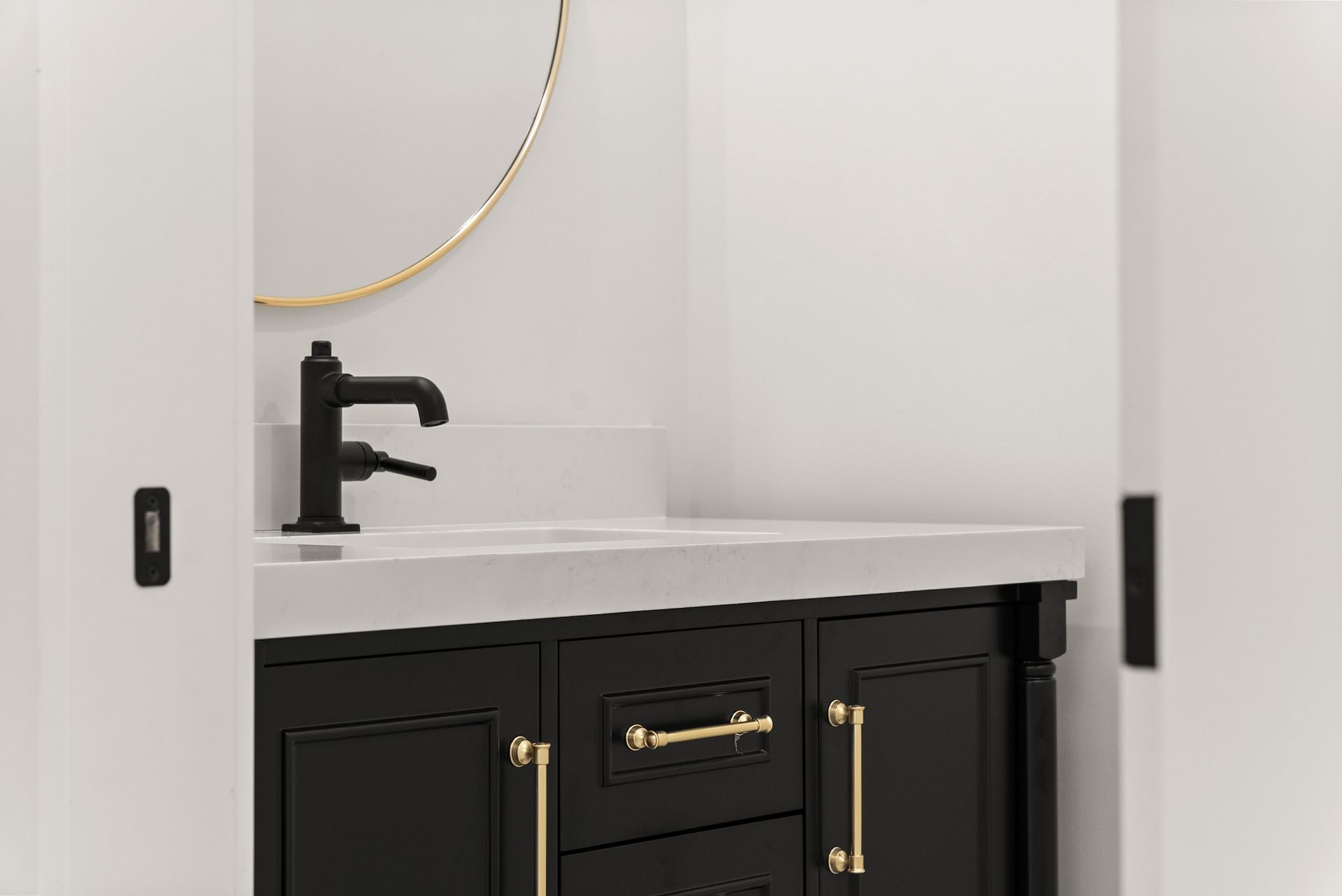 A bathroom with a black vanity , sink , mirror and faucet.