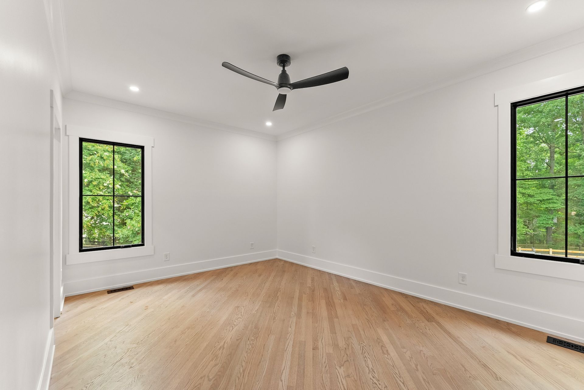 An empty room with hardwood floors and a ceiling fan.