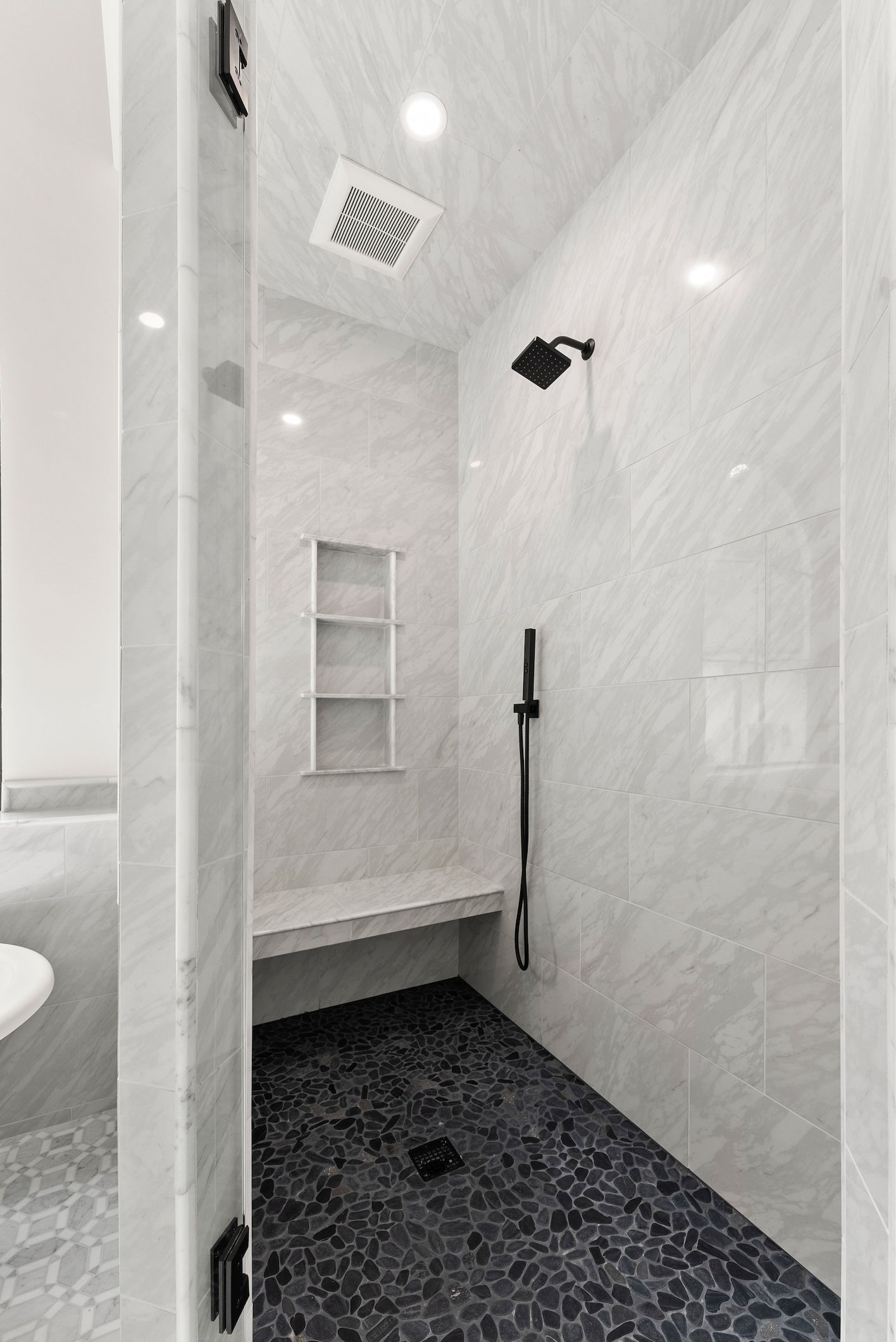 A bathroom with a walk in shower and a bench.