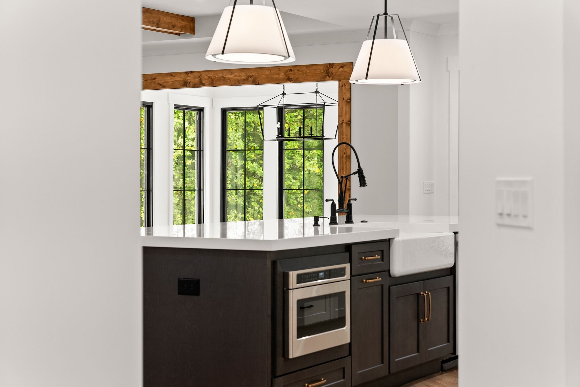 A kitchen with black cabinets , stainless steel appliances , a sink , and a large island.