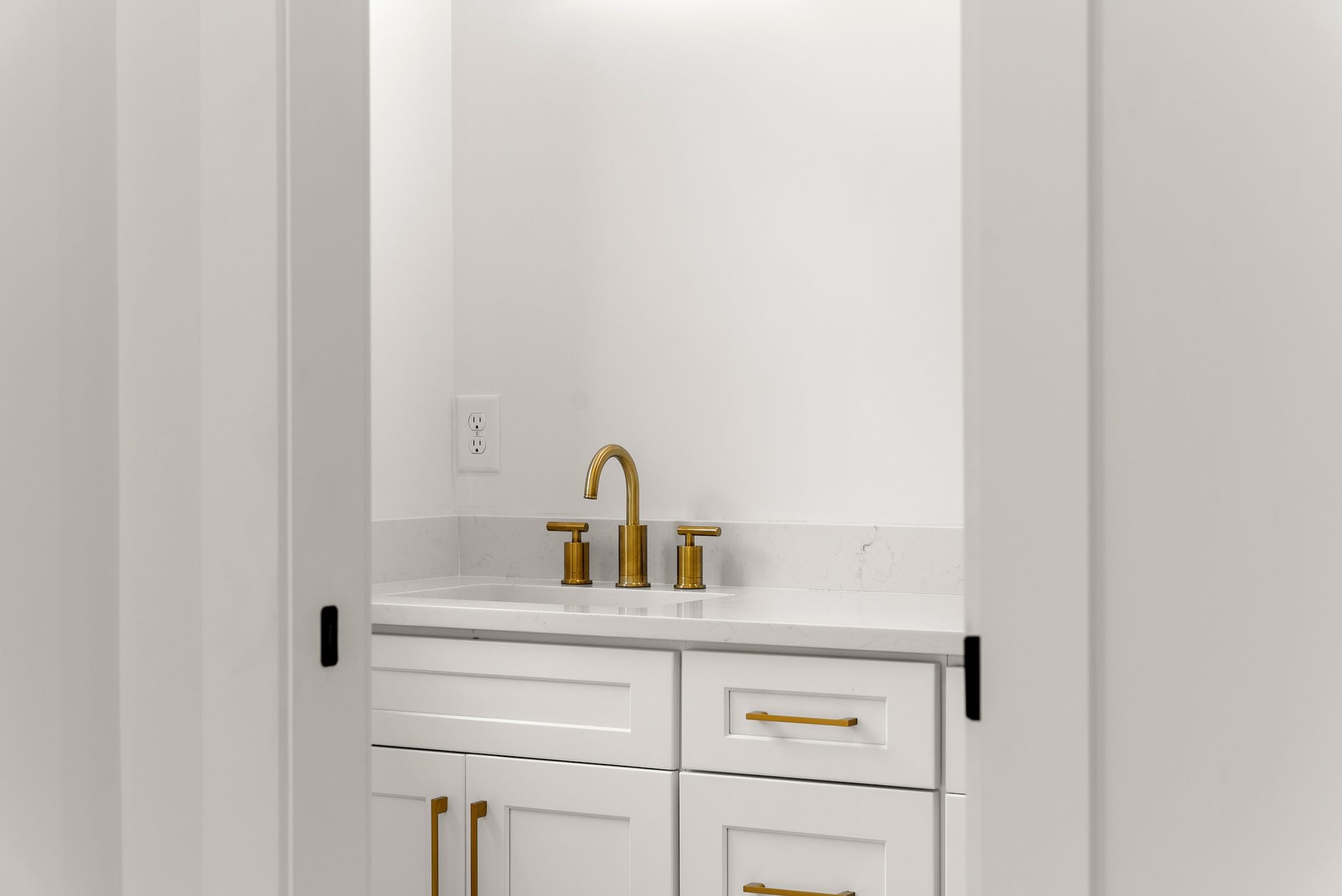 A bathroom with white cabinets , a sink , and a mirror.
