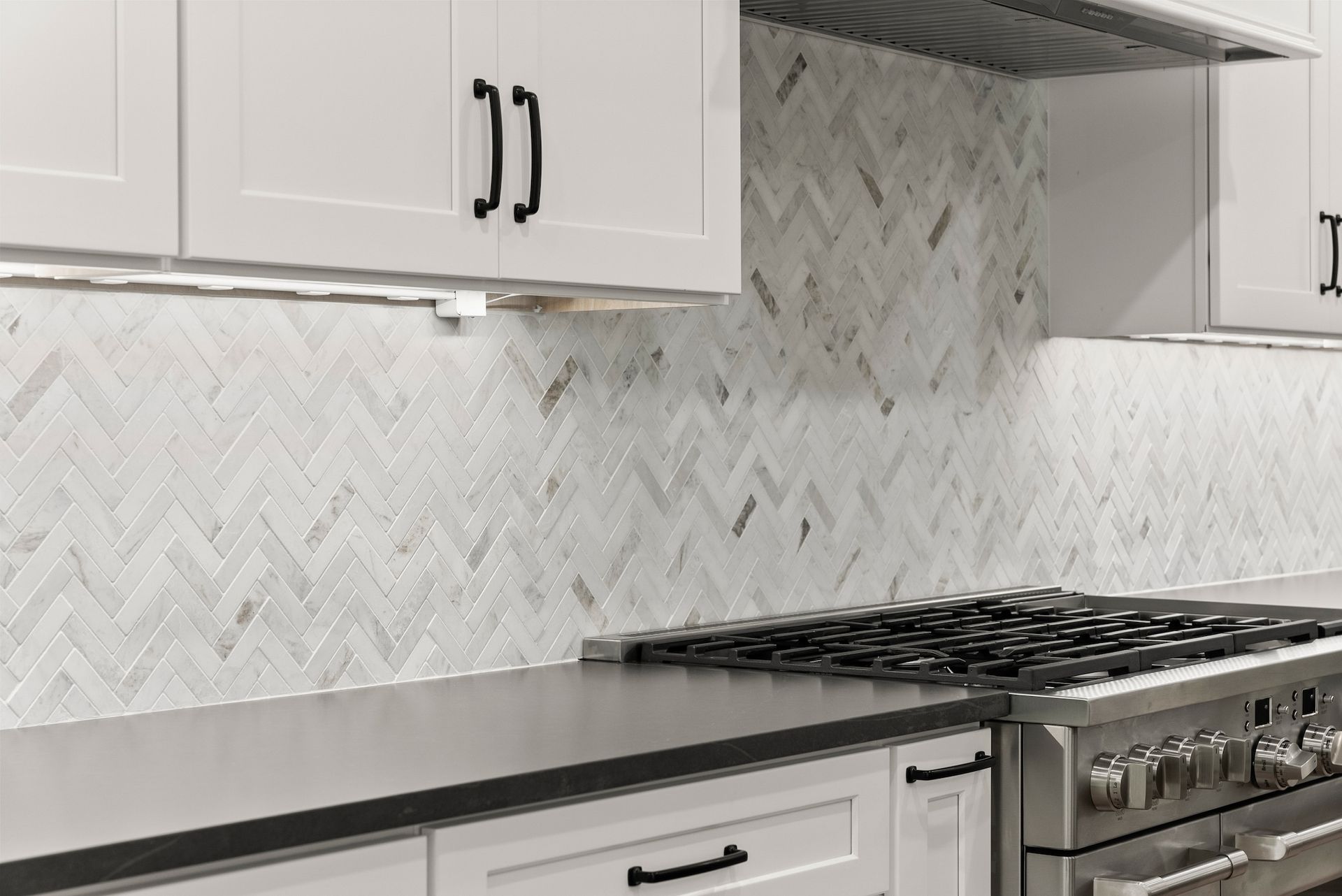A kitchen with white cabinets and a stove top oven.
