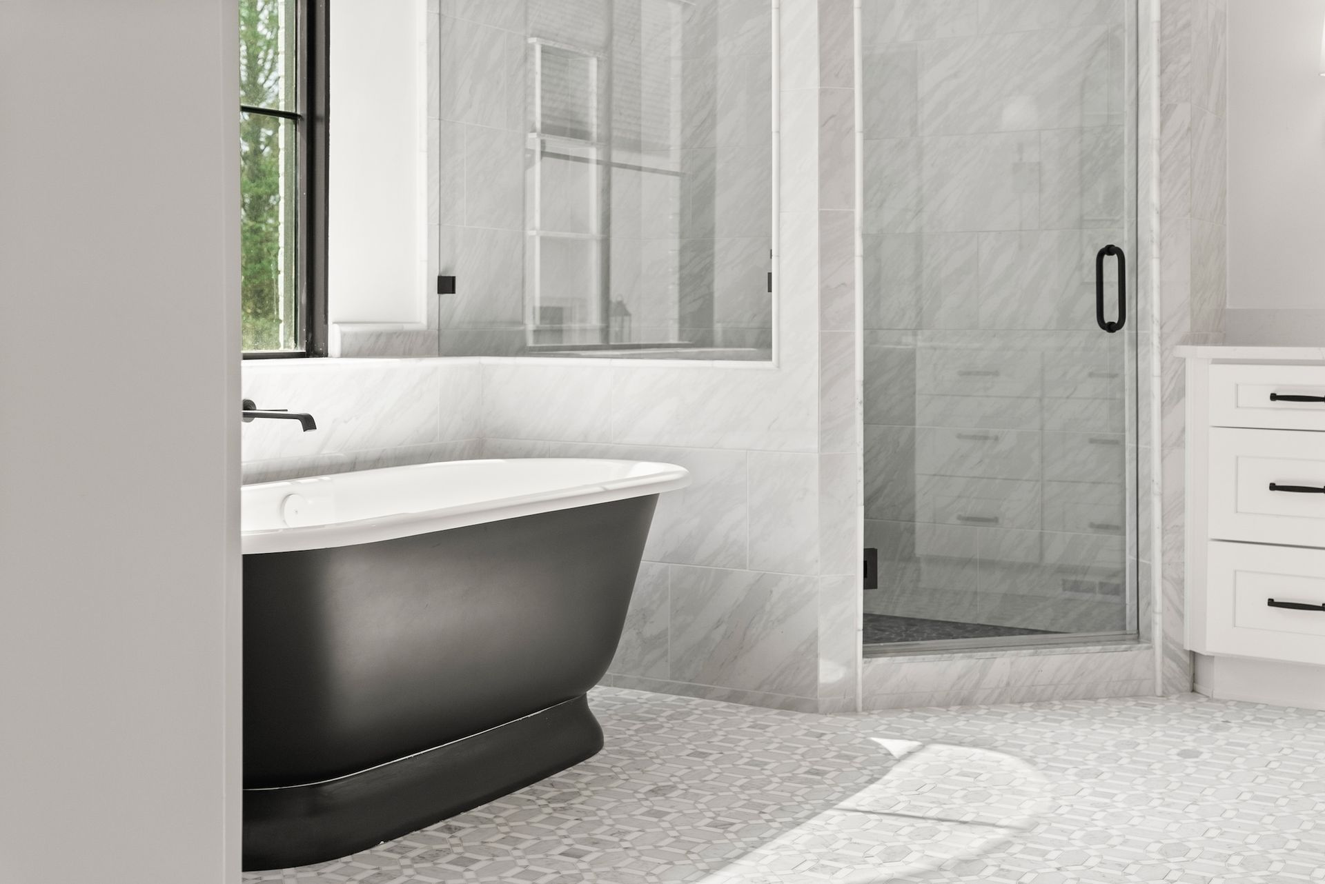 A bathroom with a black tub and a walk in shower.