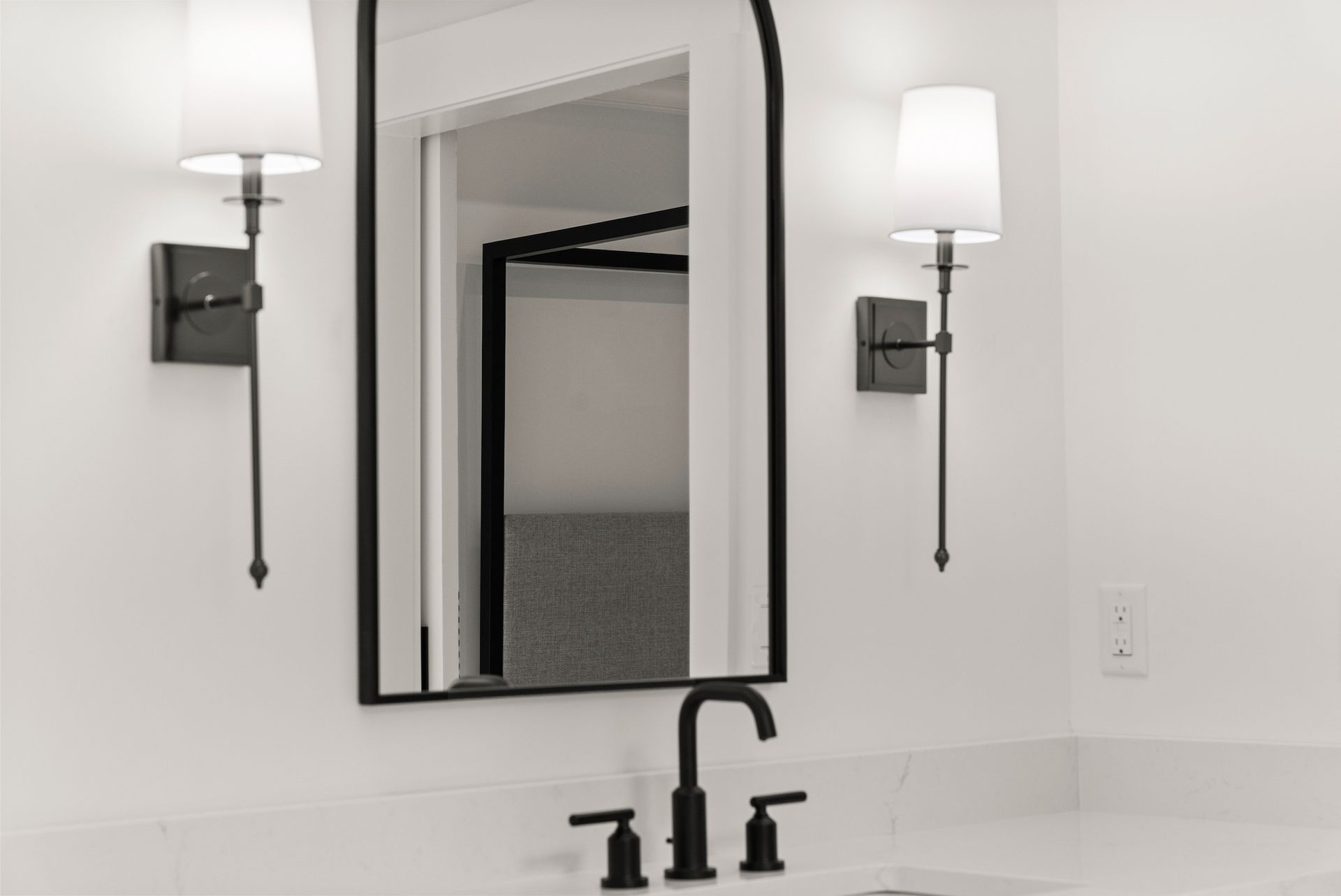 A bathroom with a sink , mirror , and two lights.