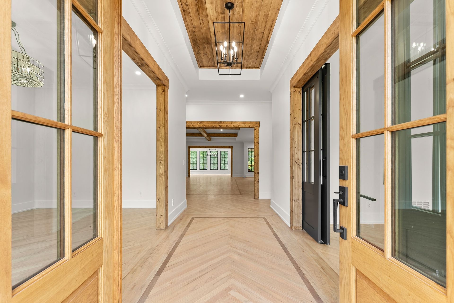 A hallway in a house with a wooden ceiling and a black door.