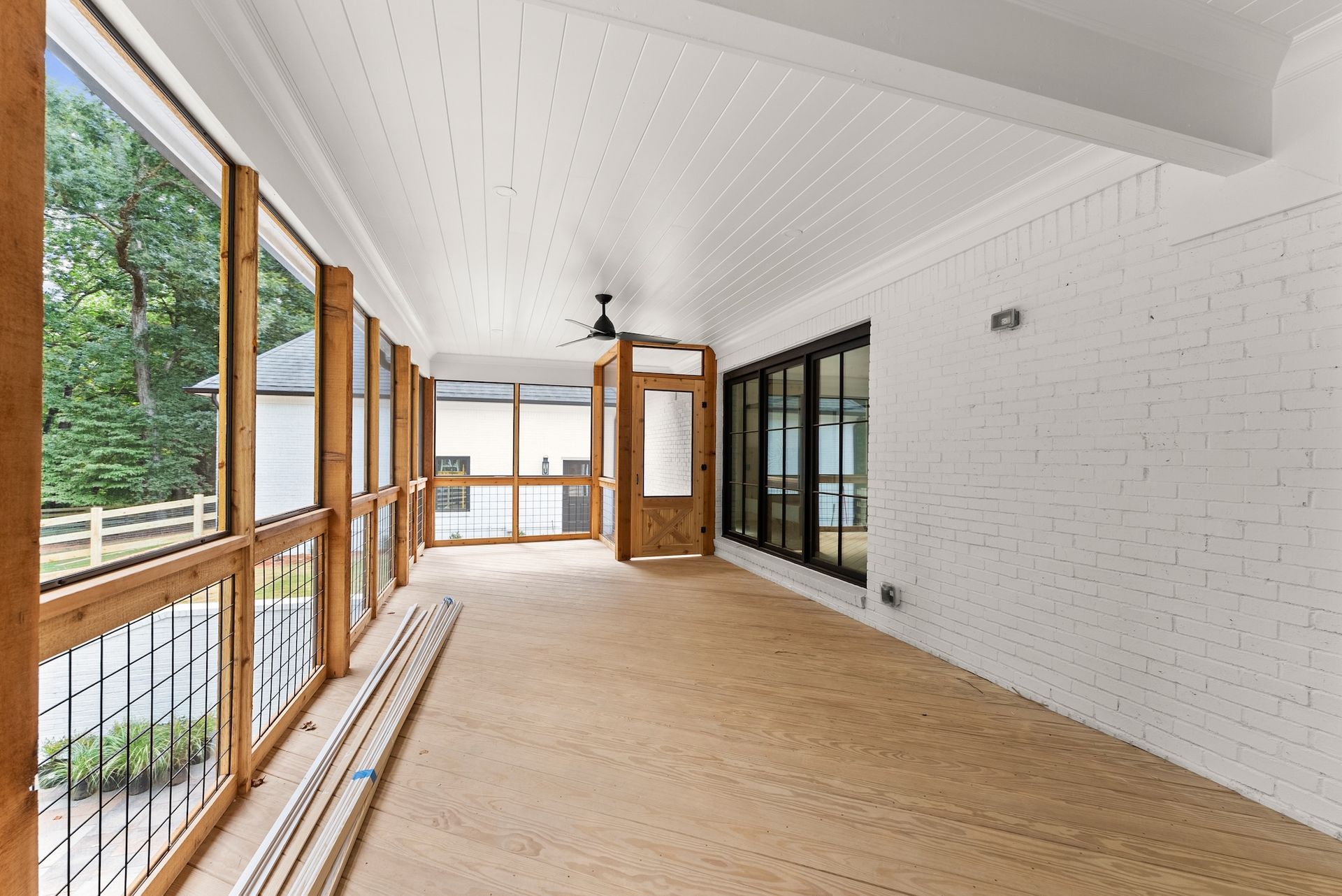 A large empty room with a lot of windows and a ceiling fan.