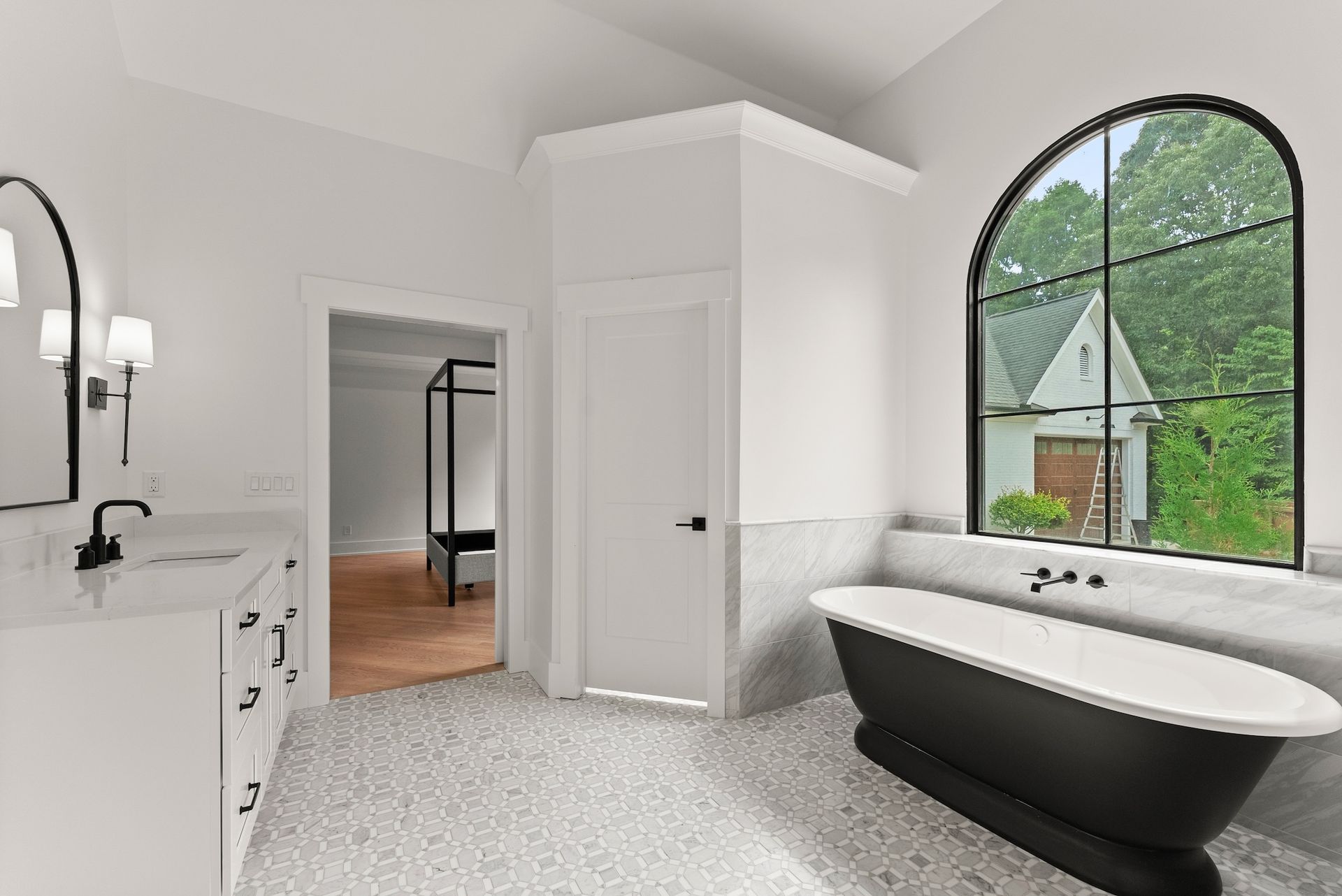 A bathroom with a black tub , sink , and window.