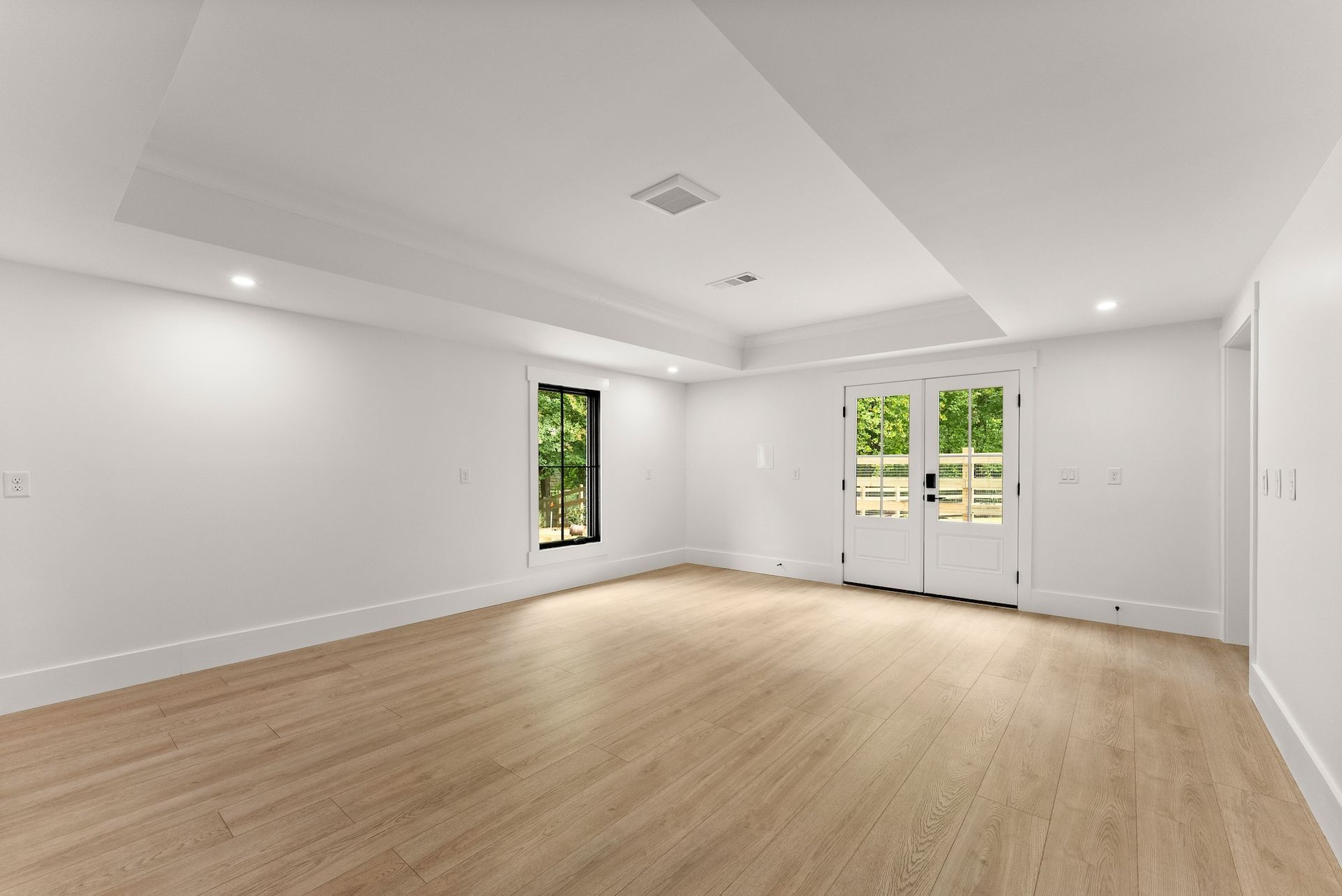 A large empty room with hardwood floors and white walls.