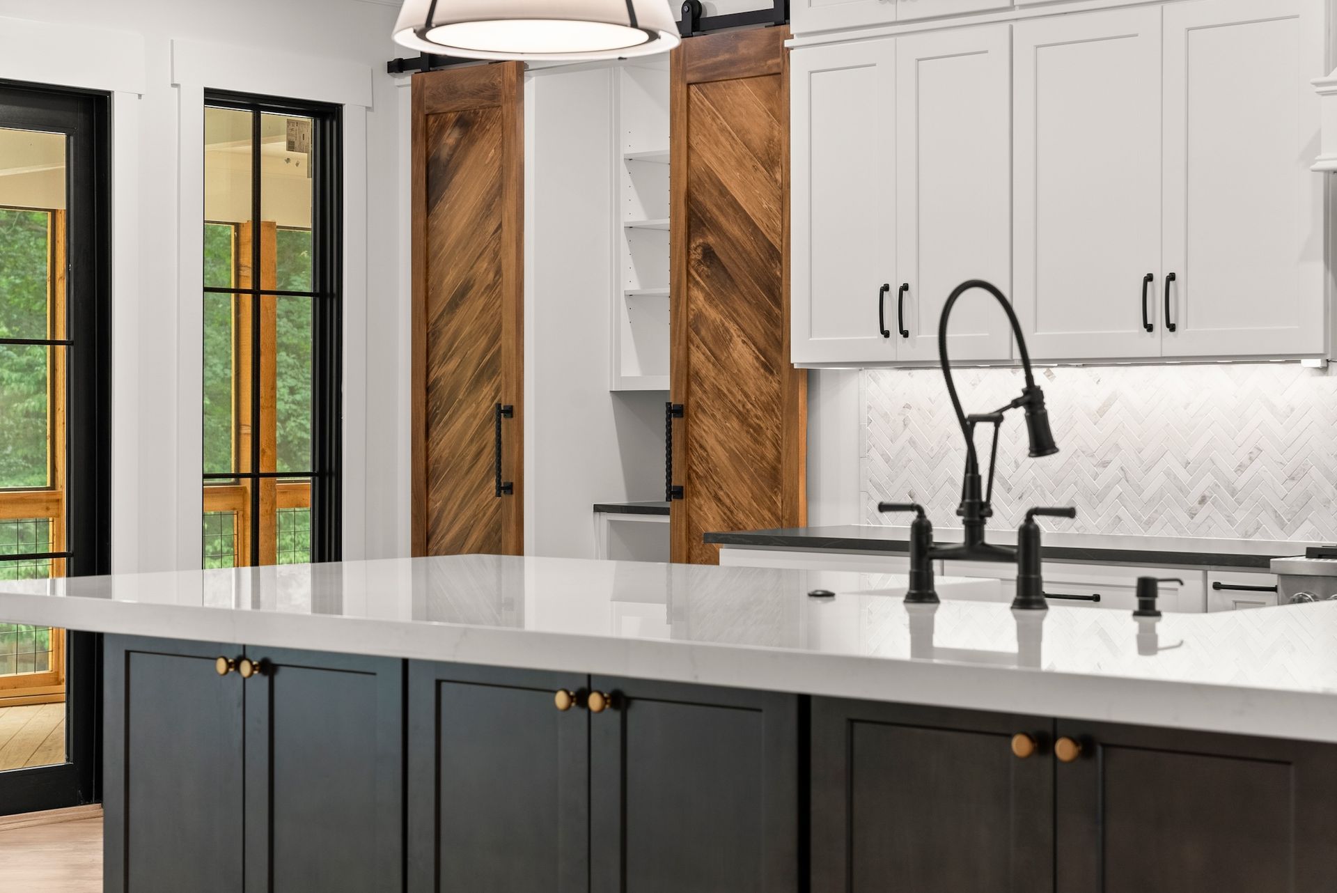 A kitchen with black and white cabinets , a large island , a sink , and a faucet.