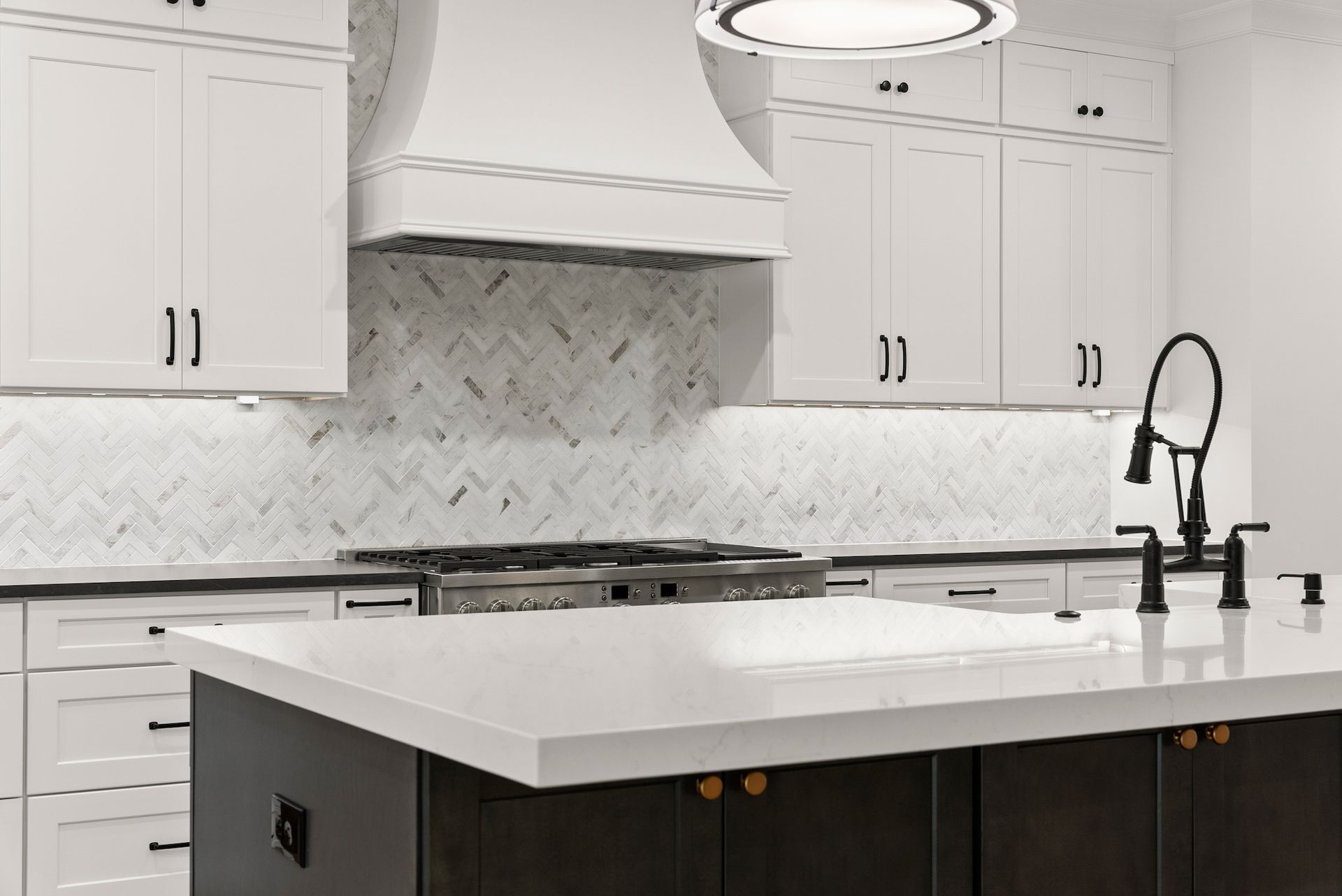 A kitchen with white cabinets , a large island , a stove and a sink.