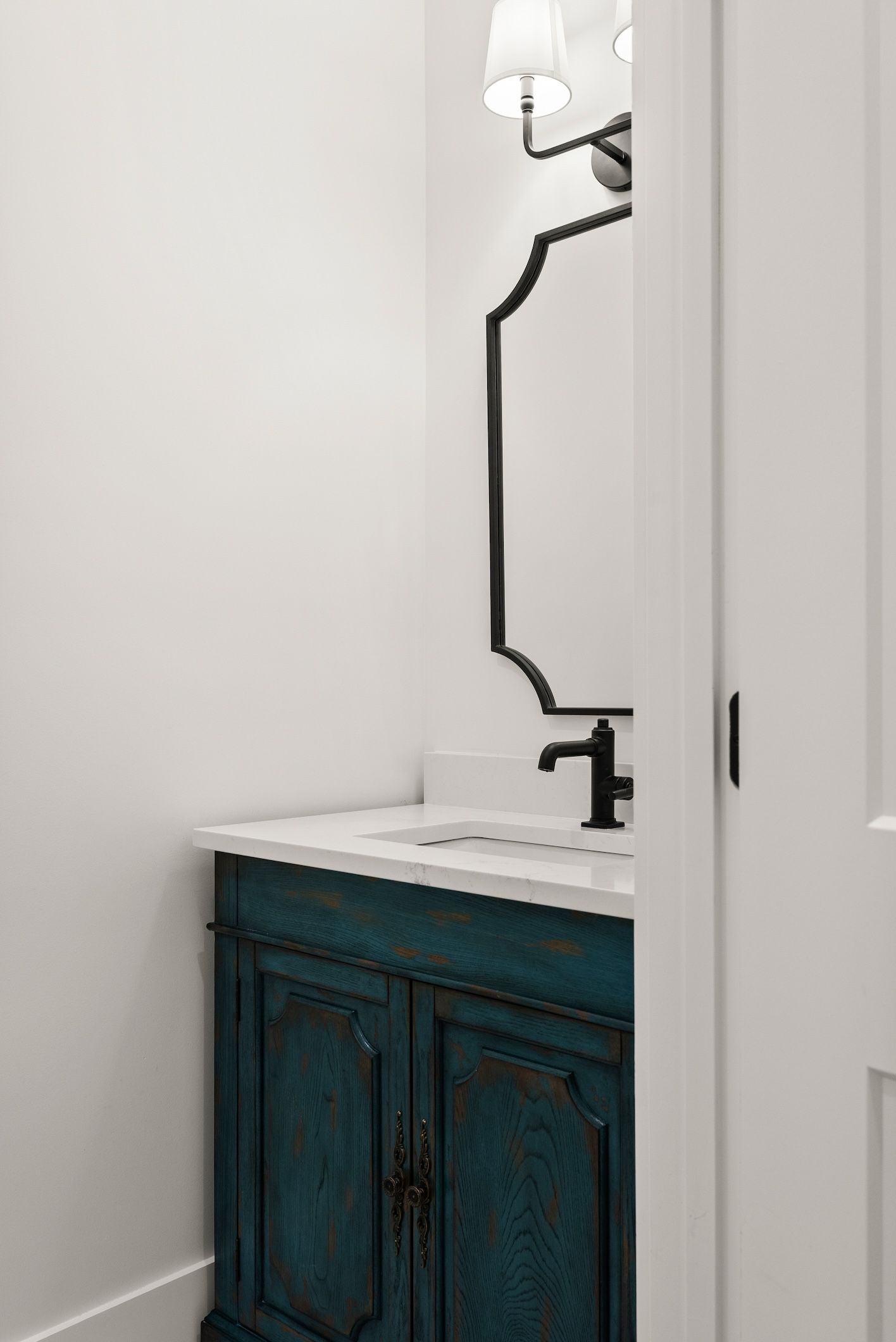 A bathroom with a blue vanity and a mirror