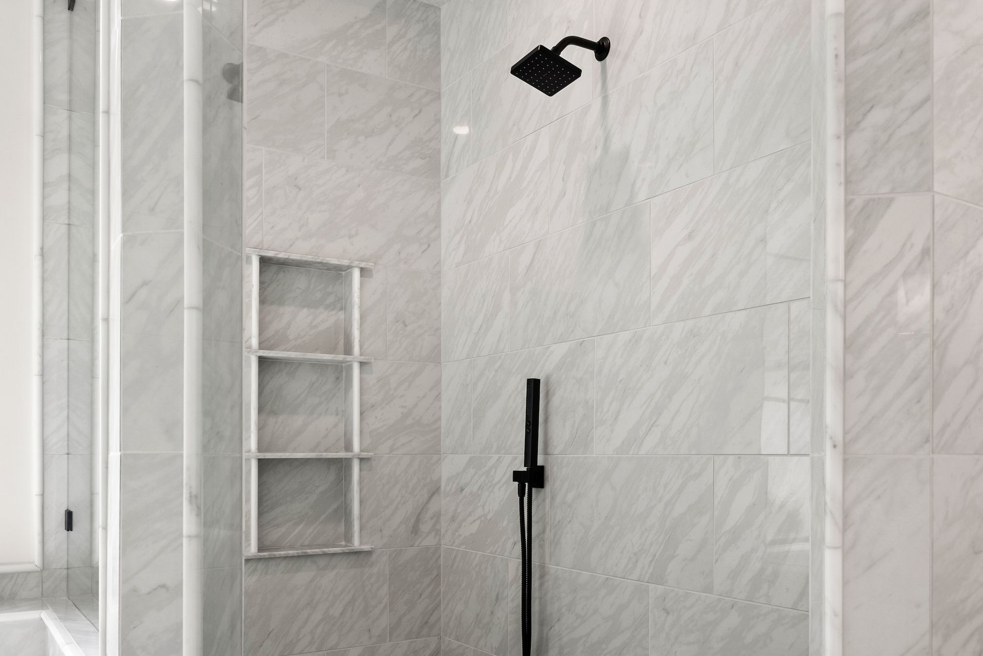 A bathroom with a walk in shower and a black shower head.